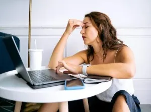 a woman thinking in front of a laptop