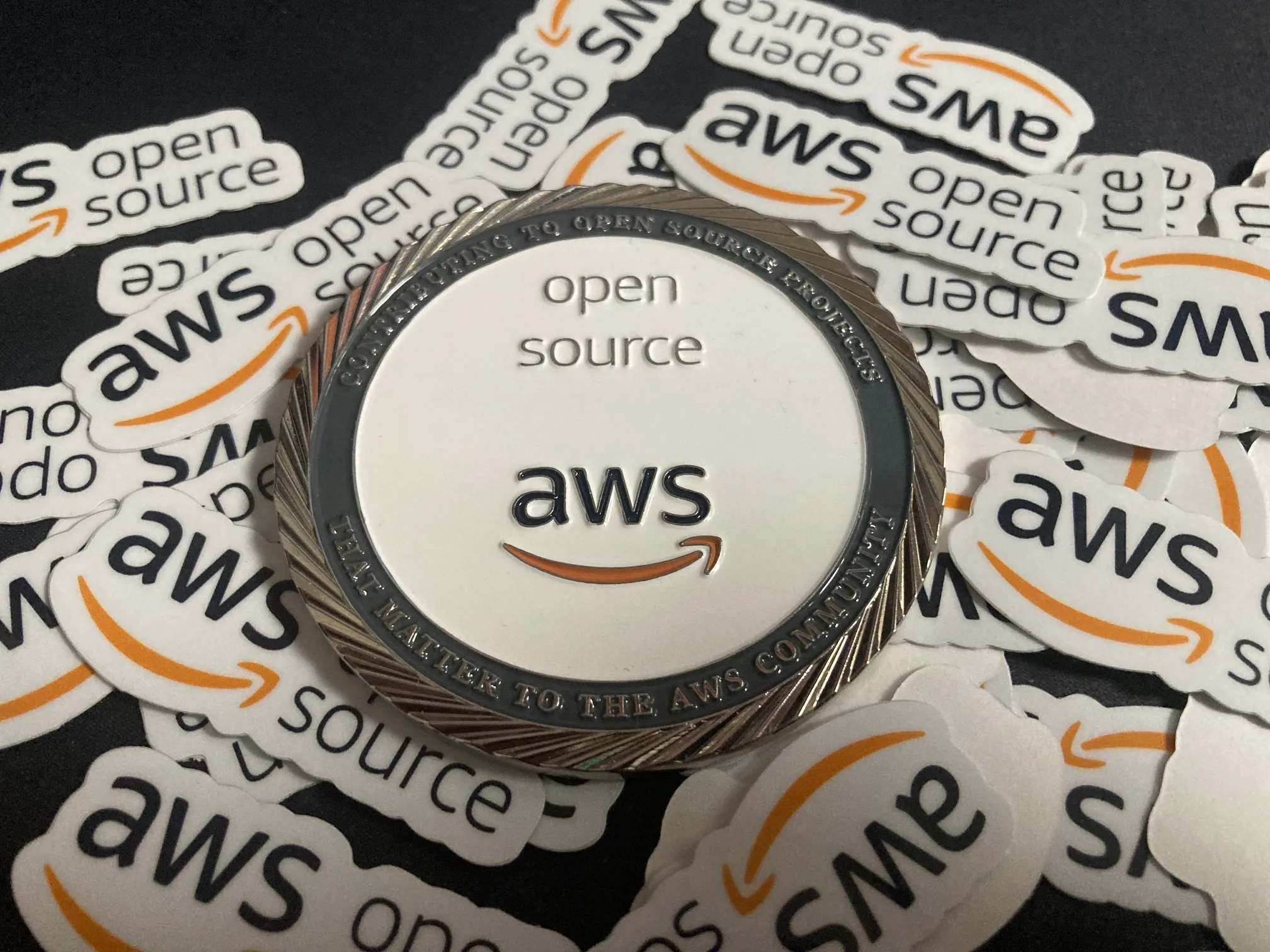 a picture of open source at aws stickers and the exclusive aws open source challenge coin